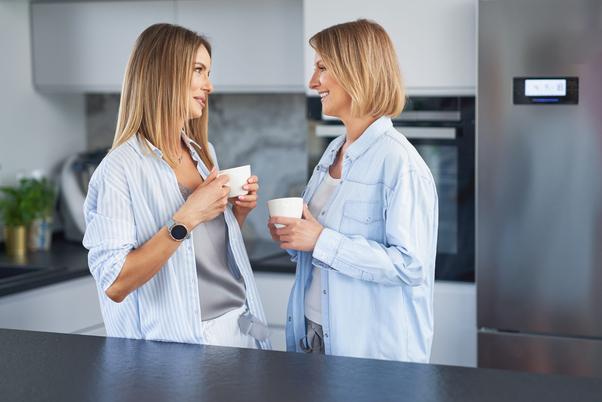 Nice two adult girls in the kitchen with coffee